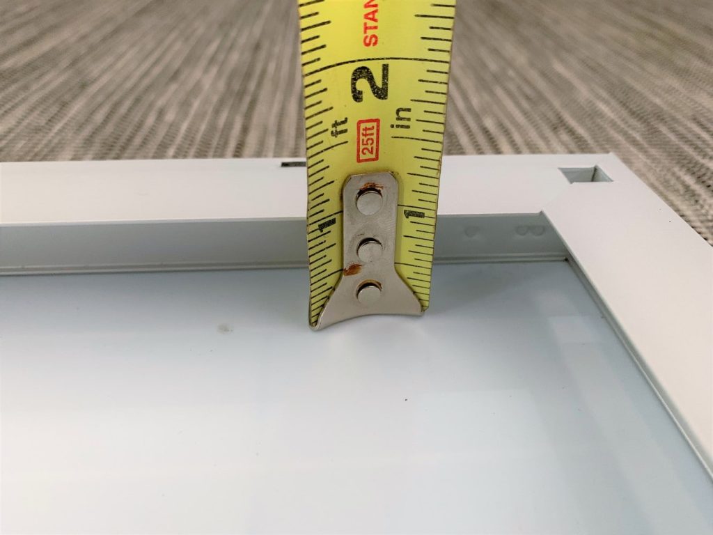 A tape measure measuring the gap between the back of a solar panel and its metal frame