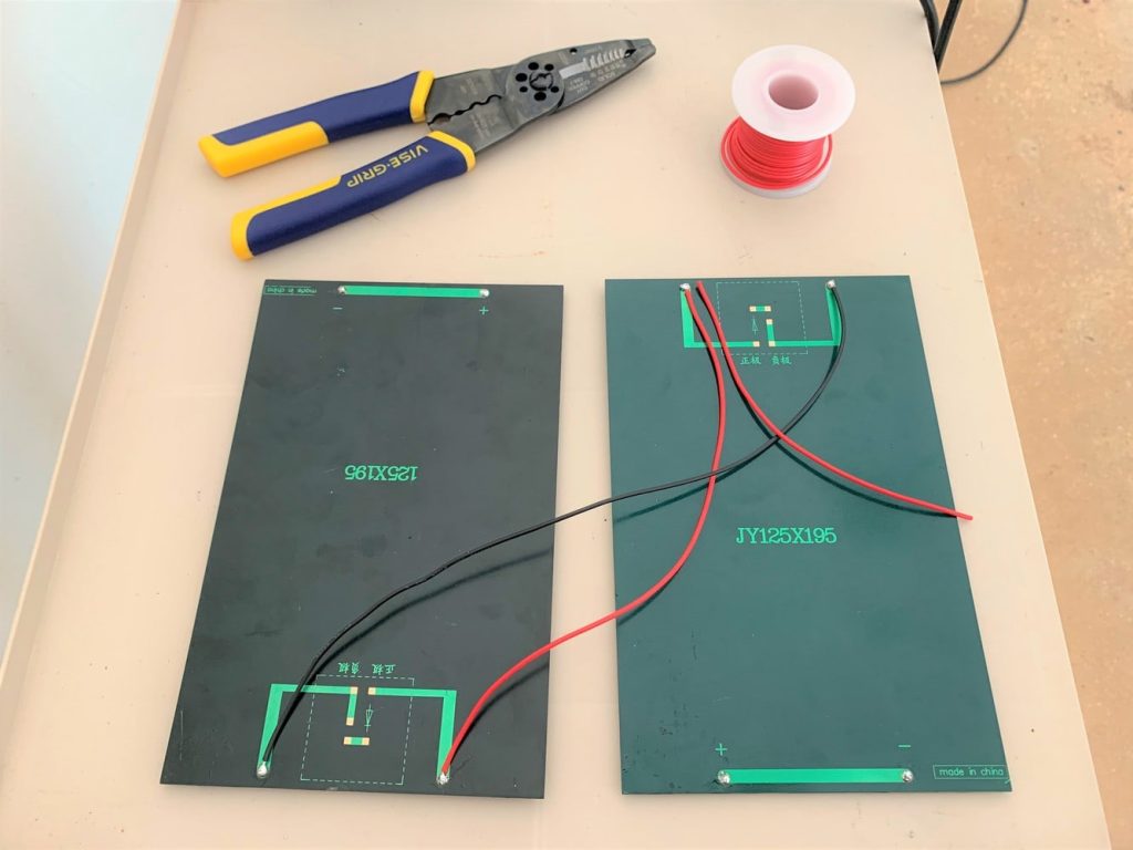 Two 3-watt solar panels wired together in parallel with a length of 22 gauge red wire on top