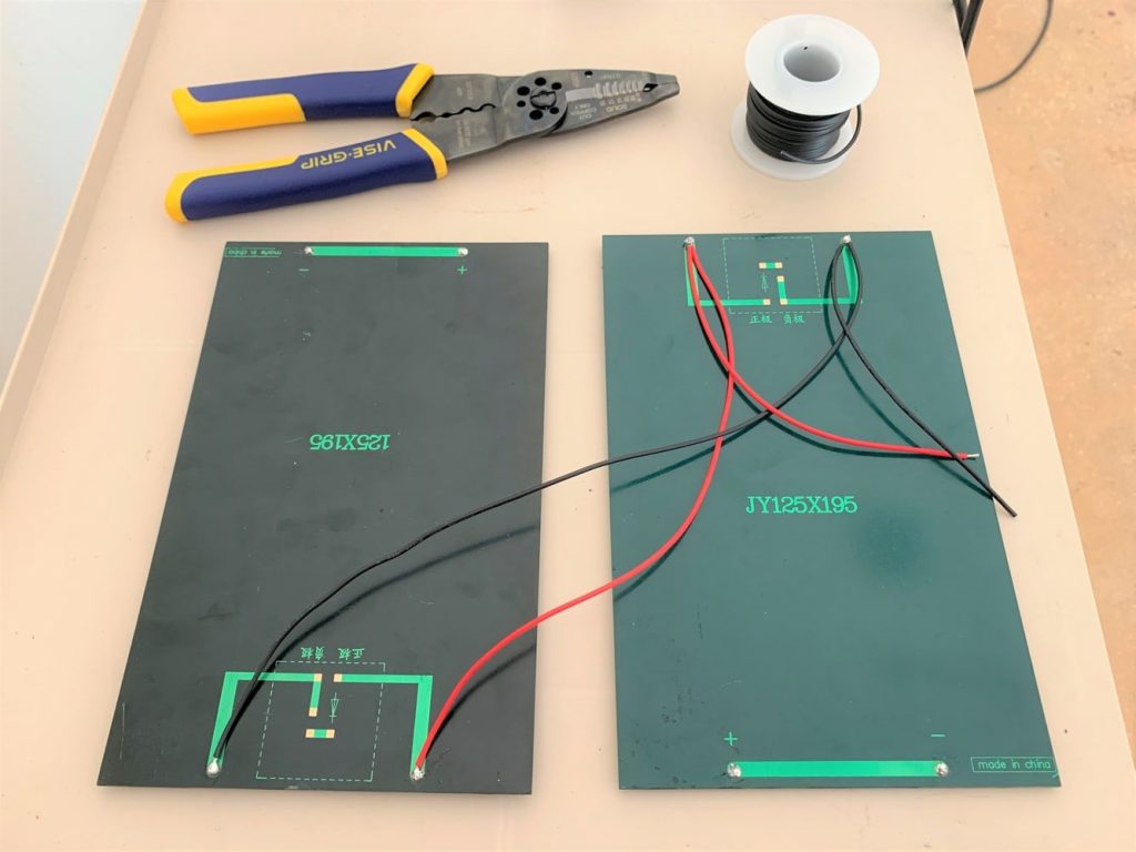 Two 333 mA solar panels wired in parallel with a red lead and a length of black 22 gauge wire resting on top