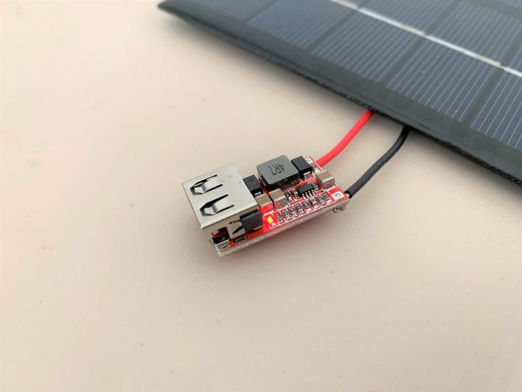 A USB buck converter with a small red LED light turned on