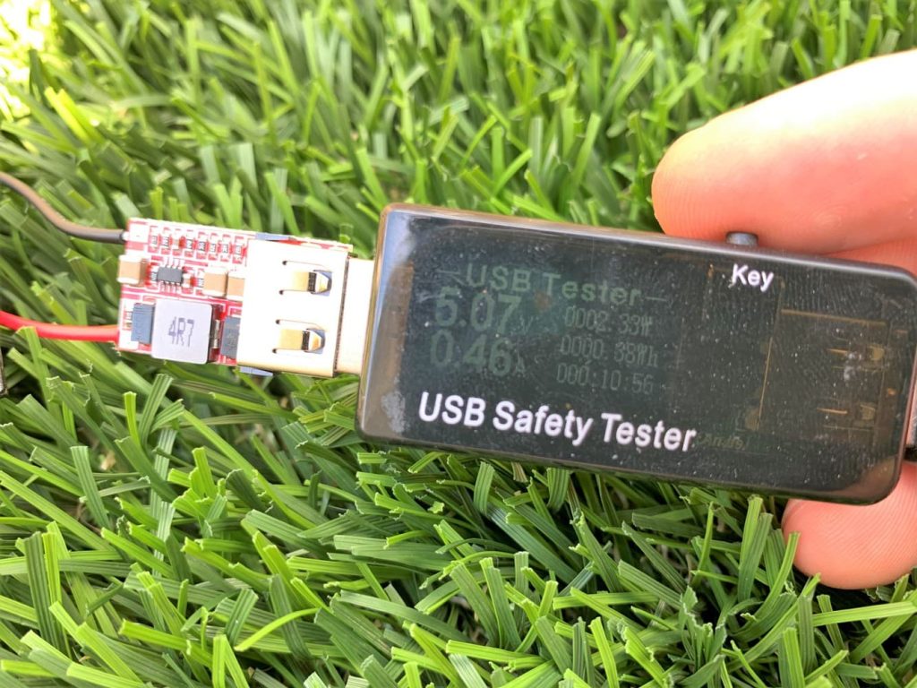 A USB meter displaying the voltage and amperage output of the solar charger
