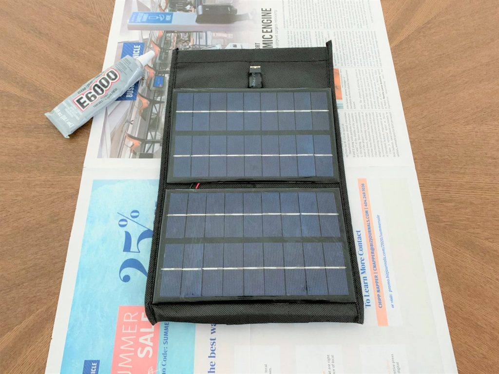 Solar panels glued to a strip of fabric laid on top of a piece of newspaper