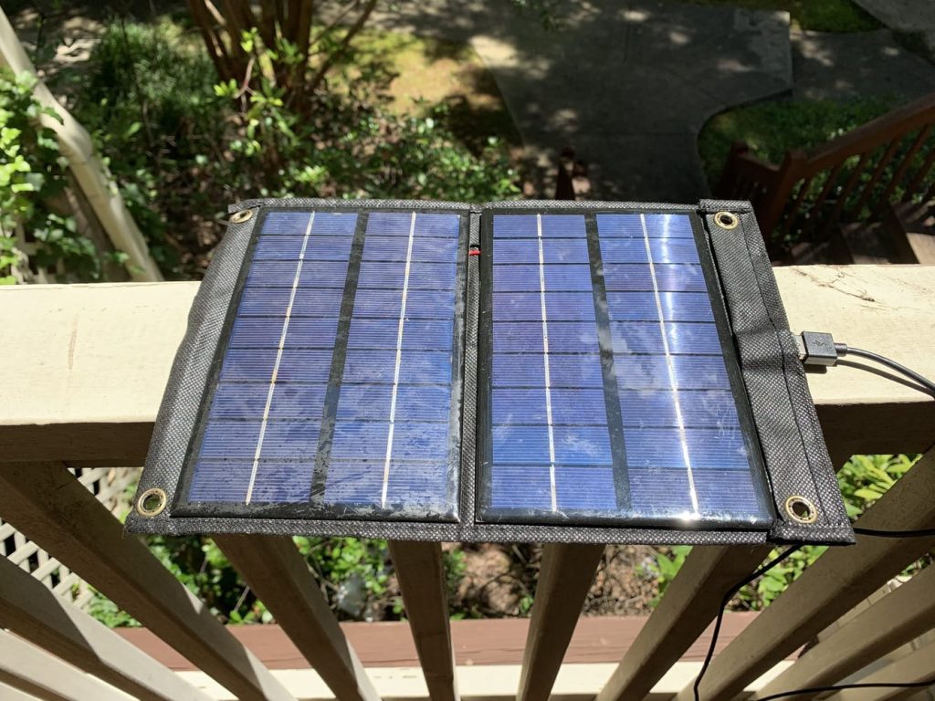 A solar charger resting on a handrail in direct sunlight