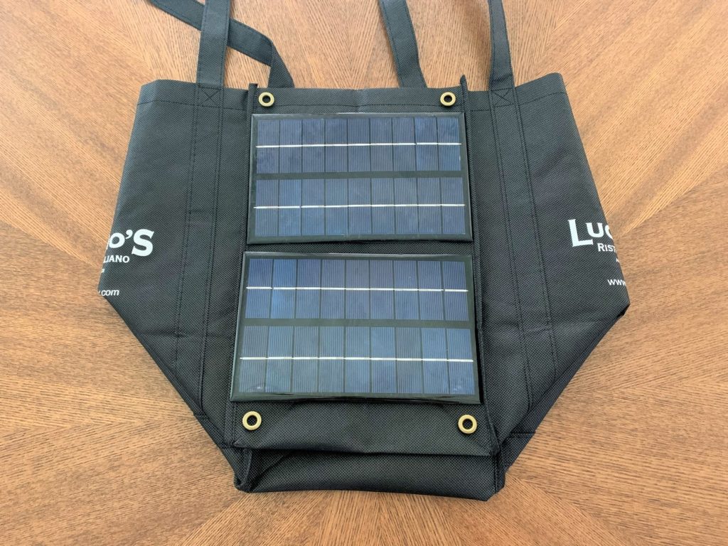 Two 3W 9V solar panels and four eyelets laid on top of a reusable grocery bag