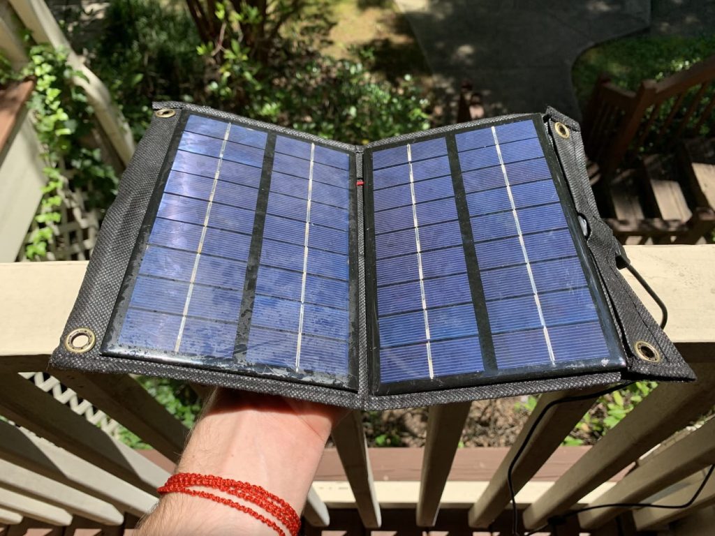 A solar charger being held in direct sunlight on a balcony