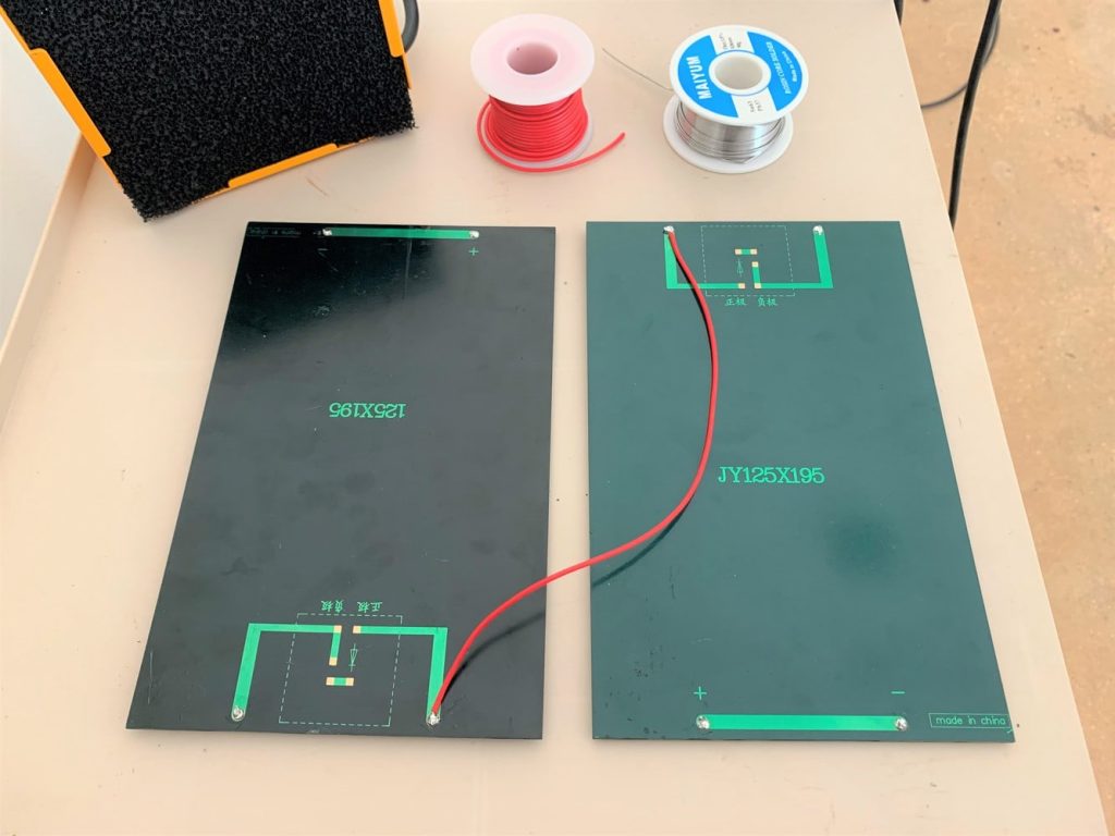 Two solar panels wired together with a red wire